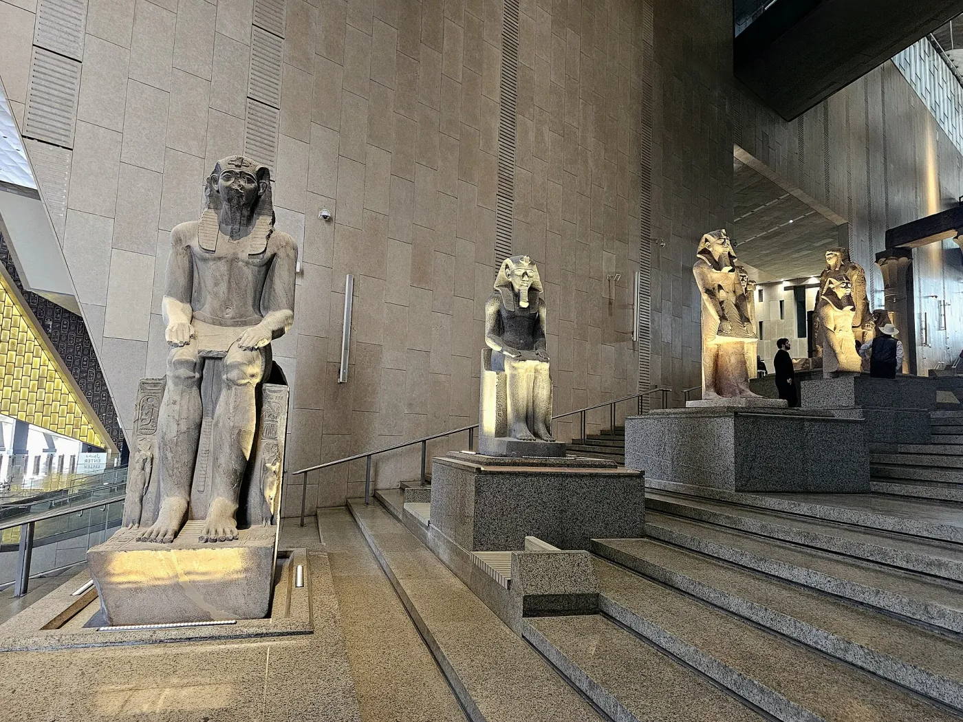 The grand staircase of the Grand Egyptian Museum lined with ancient statues